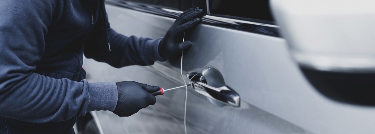 autodief is auto aan het open breken met een schroevendraaier